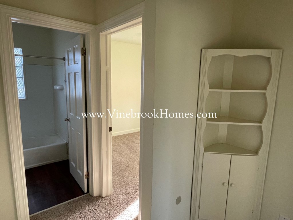 a closet with shelves and a door into a bathroom