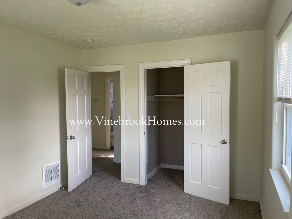 a walk in closet in a bedroom with two doors and a window