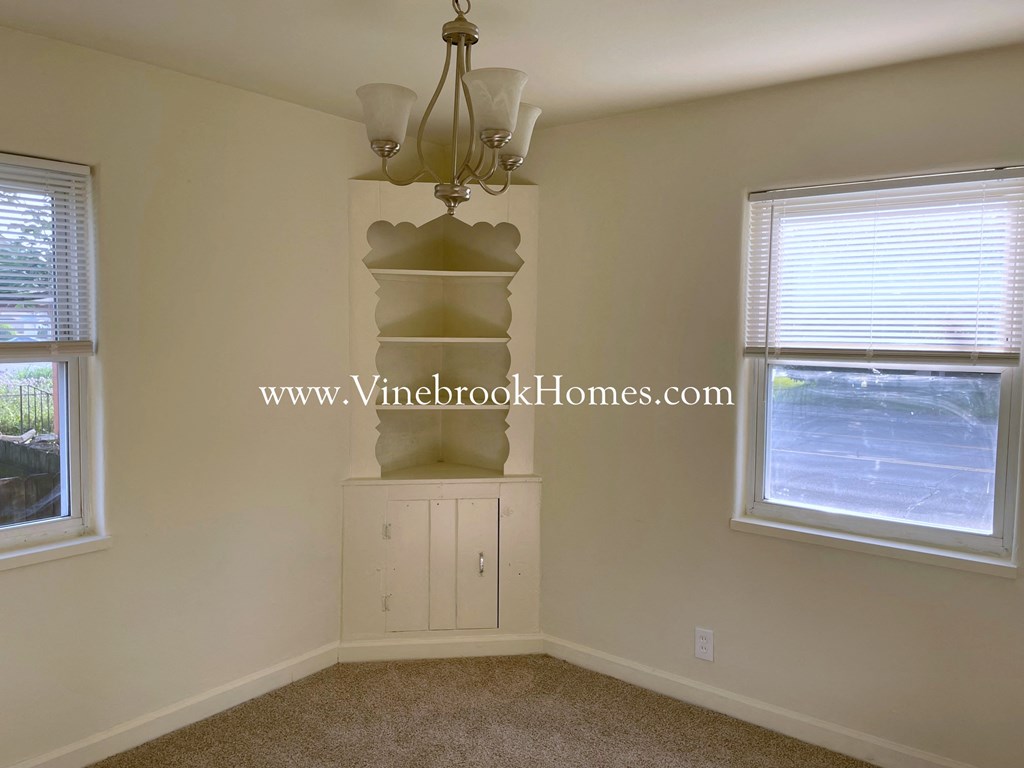 a corner room with a cabinet and a chandelier
