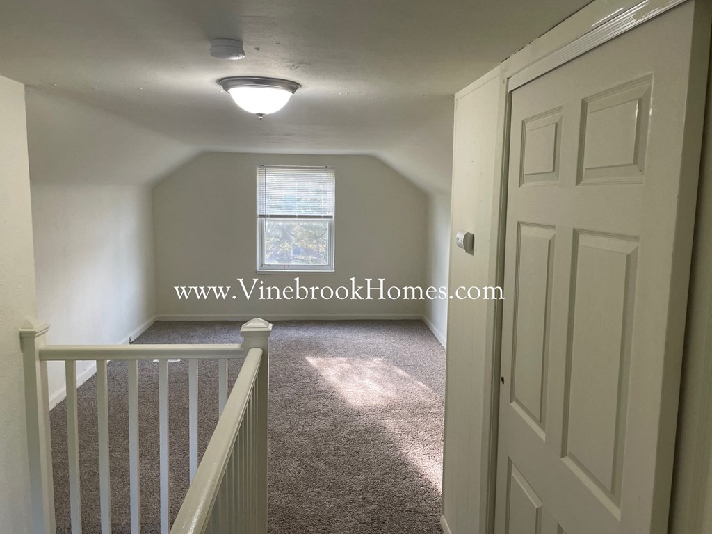 a small upstairs room with a staircase and a window