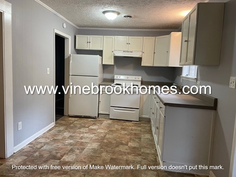 A kitchen with a refrigerator, cabinets, and a countertop.