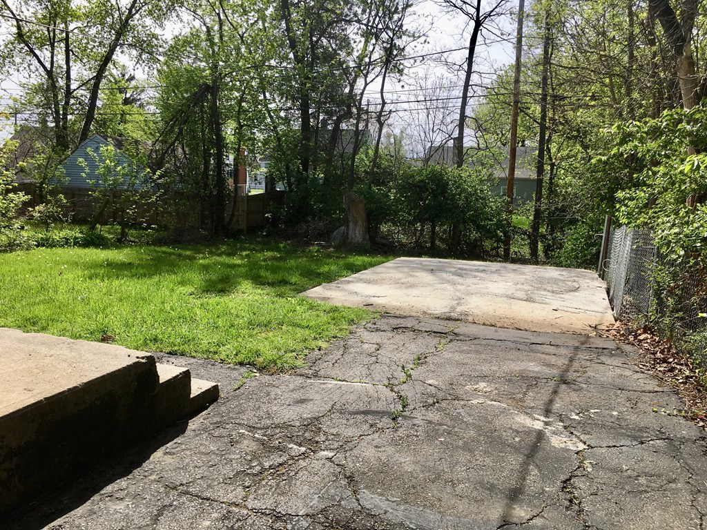 a yard with a concrete driveway and a fence