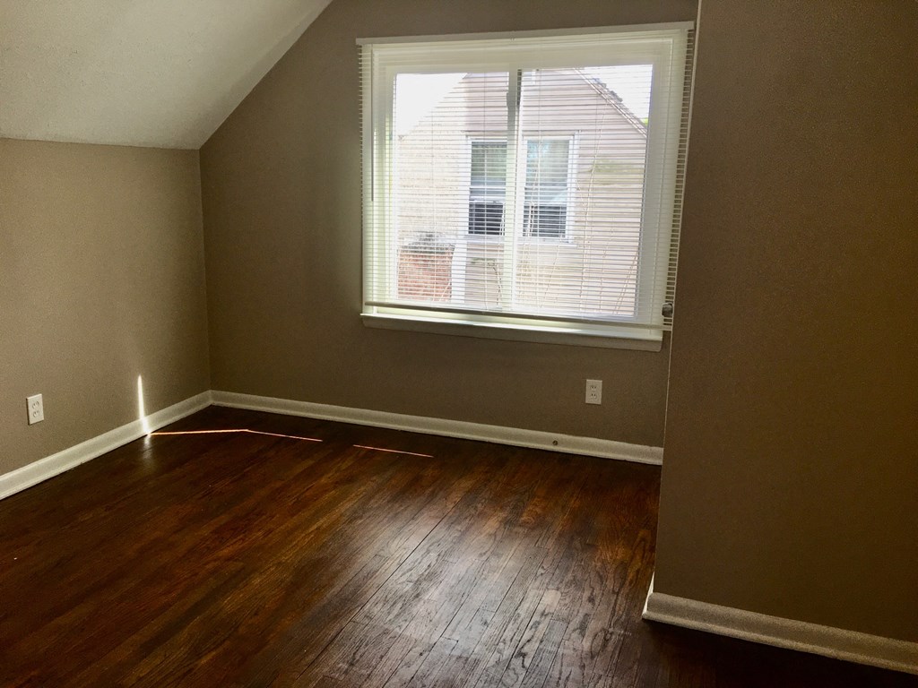 an empty room with a window and wooden floors