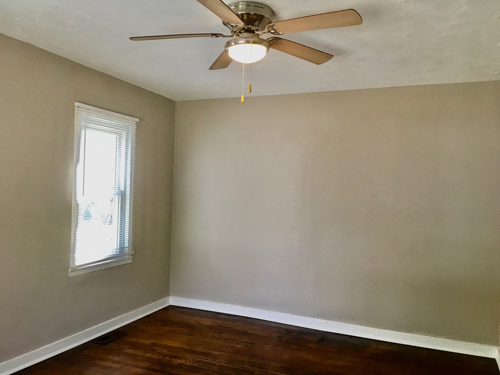 an empty room with a ceiling fan and a window