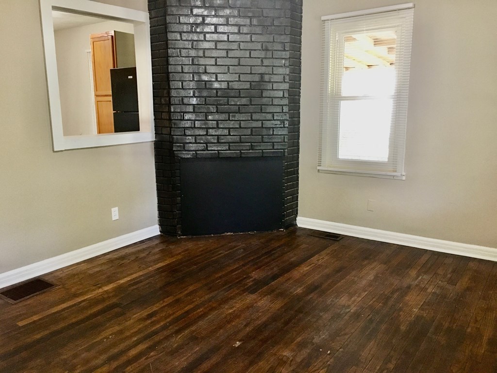 a living room with a black brick fireplace and wooden floors
