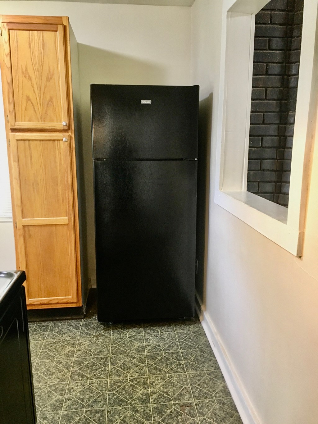 a black refrigerator in a kitchen next to a window