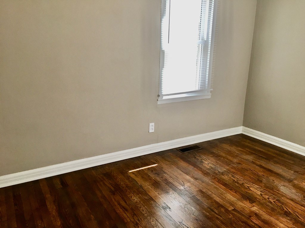 an empty room with wooden floors and a window