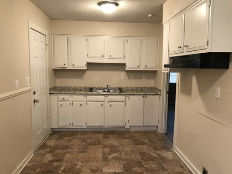 an empty kitchen with white cabinets and a sink