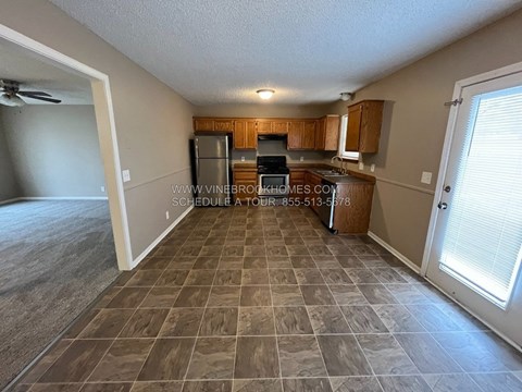 A kitchen with tile flooring and wooden cabinets.