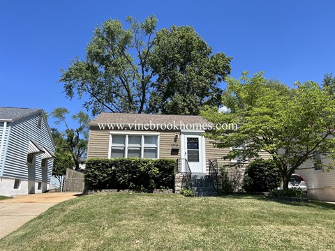 a small brown house with a yard and a tree