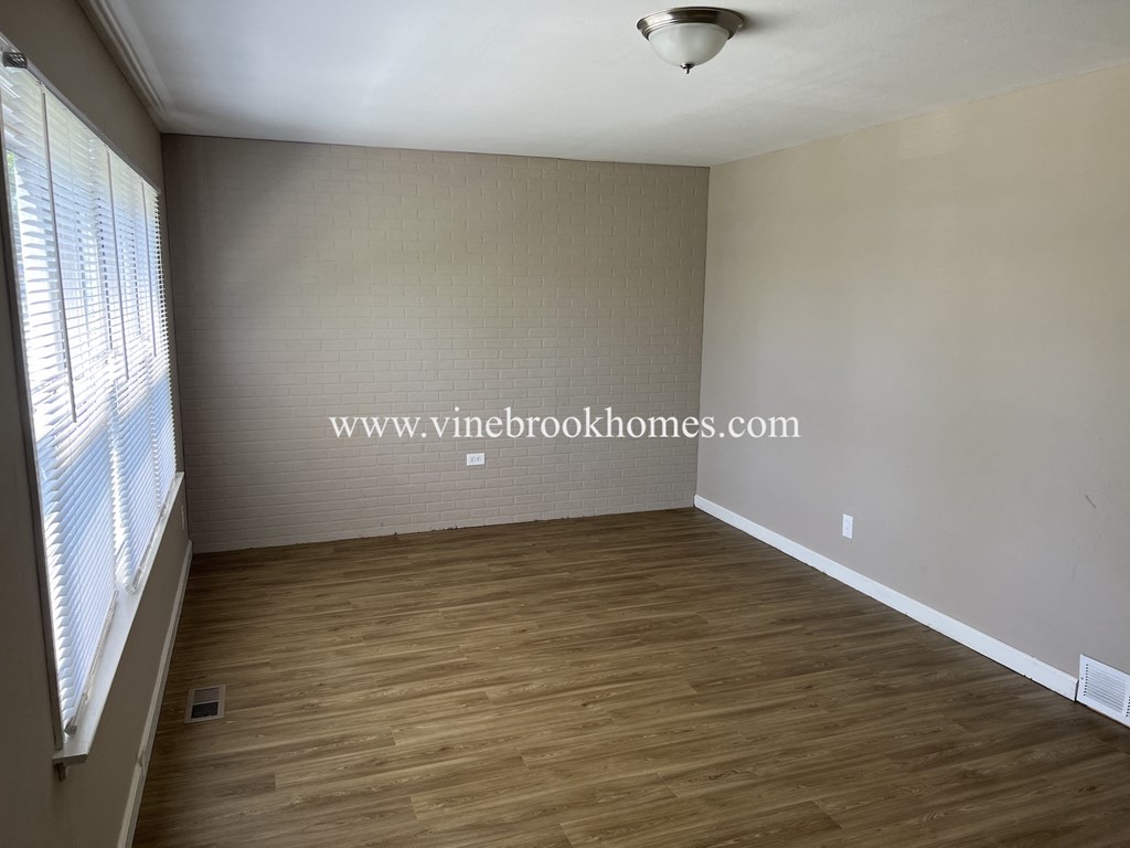 an empty living room with wood flooring and a window