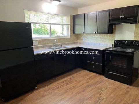 a kitchen with black cabinets and a stove and a window