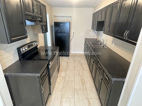 A kitchen with black cabinets and a black refrigerator.