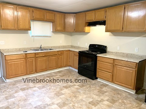 A kitchen with wooden cabinets and a black oven.