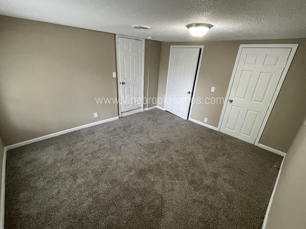 a bedroom with two doors and a carpeted floor