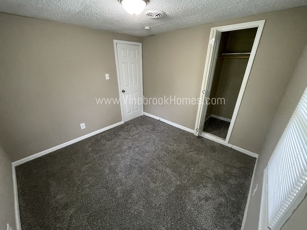 a bedroom with a carpeted floor and a door to a closet
