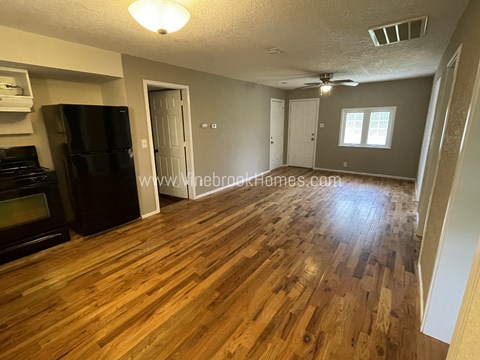A kitchen with a black fridge and wooden floors.