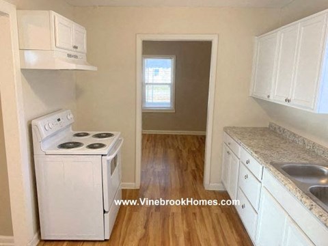 A small kitchen with a white stove and cabinets.