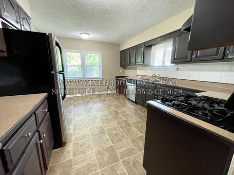 A kitchen with black appliances and brown cabinets.