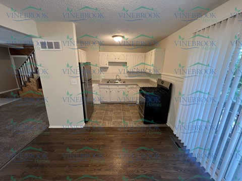 A kitchen with a refrigerator, sink, and stove is shown with a Vinebrook Homes watermark.