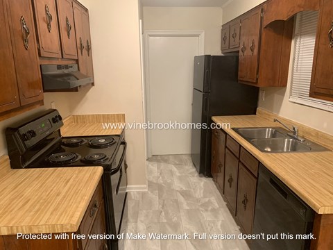 A kitchen with wooden cabinets and a black refrigerator.