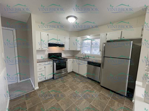 a remodeled kitchen with white cabinets and stainless steel appliances