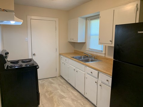 A kitchen with black appliances and white cabinets.