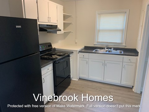 A kitchen with a black fridge and white cabinets.