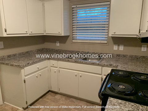a kitchen with white cabinets and granite counter tops