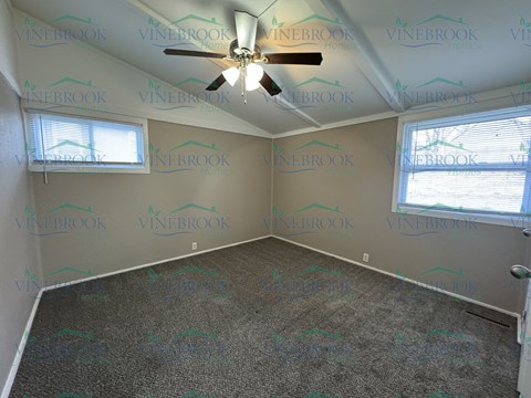a bedroom with a ceiling fan and a carpet