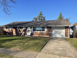 a small brick house with a driveway and a white garage door