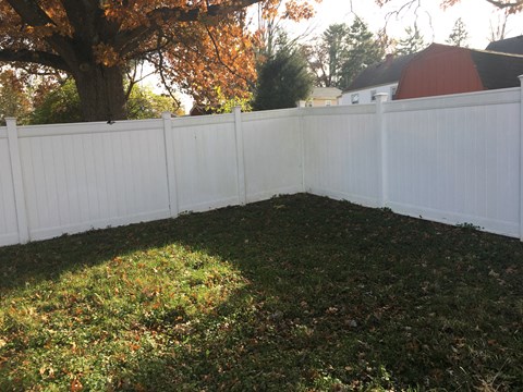 a white fence in a backyard with green grass
