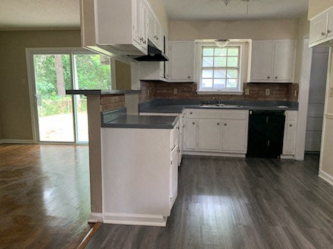 an empty kitchen with white cabinets and black counter tops
