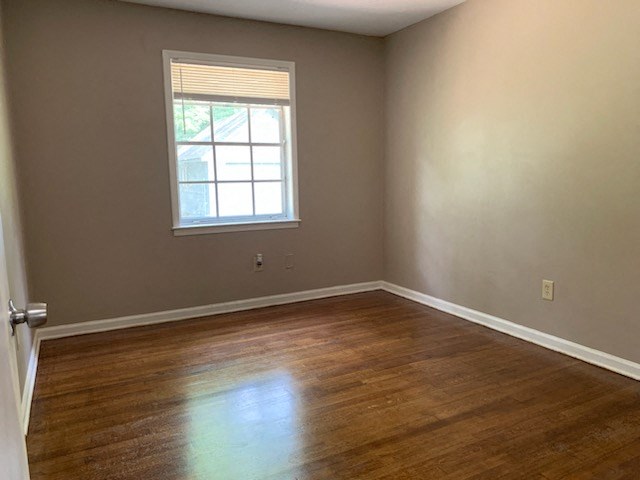 a empty room with a window and wooden floors