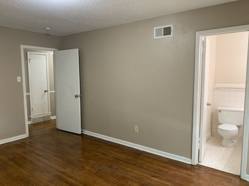 an empty bathroom with a toilet and a door to a closet