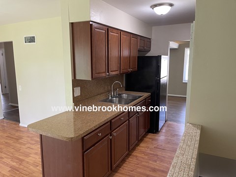 a kitchen with wooden cabinets and a sink and a black refrigerator