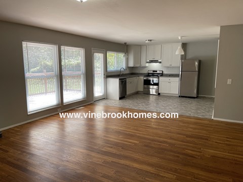 an open kitchen and living room with wood floors and white cabinets
