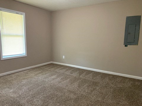 an empty room with a window and a gray carpet