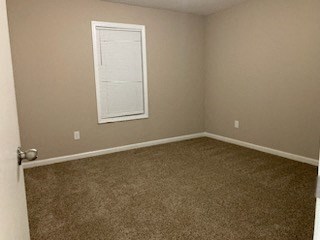 a empty room with a window and a brown carpet