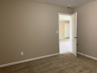 an empty living room with a door open to a hallway