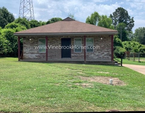 a small brick building sitting in a grass field