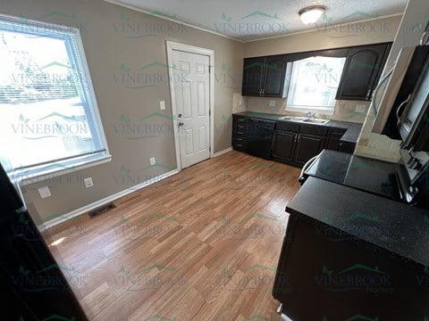 a remodeled kitchen with wood flooring and black cabinets