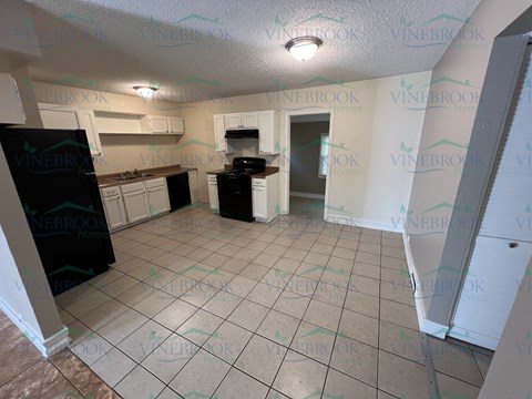 a kitchen with white cabinets and black appliances and a tile floor