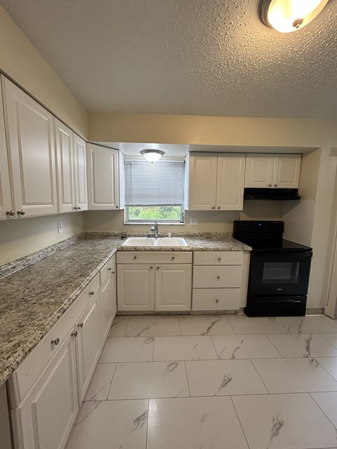 A kitchen with granite countertops and white cabinets.