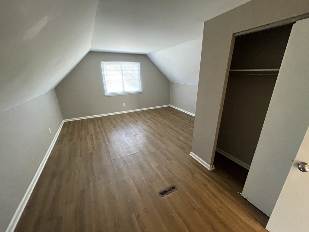 an empty room with hardwood floors and a closet