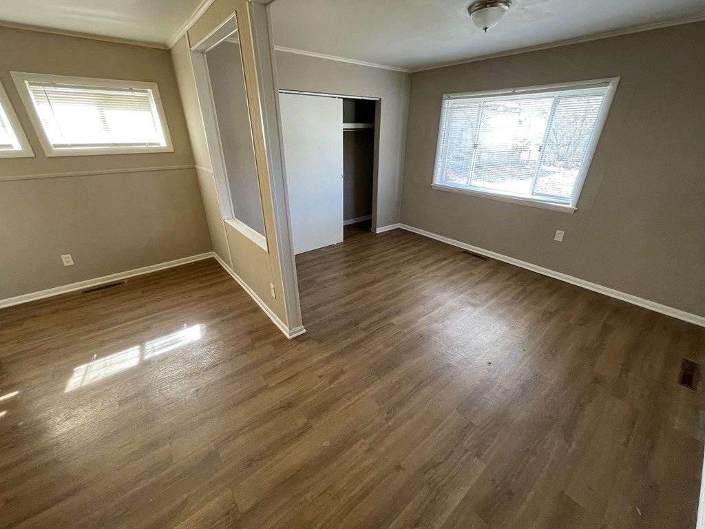an empty living room with wooden floors and a window