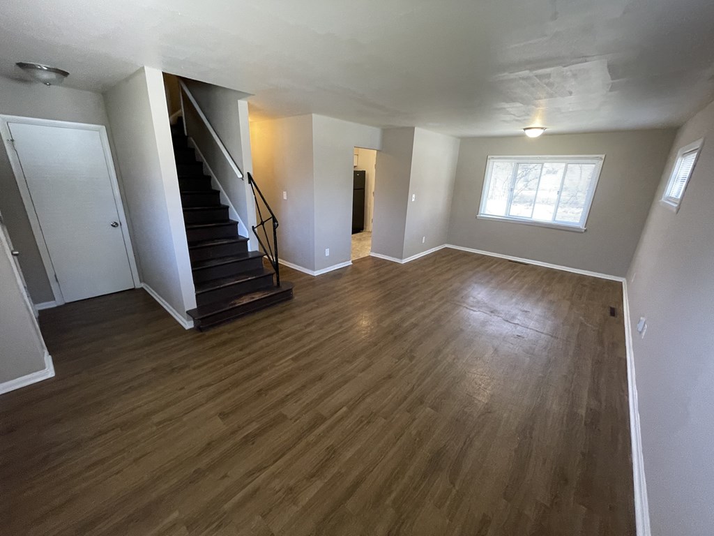 an empty living room with hardwood floors and a staircase