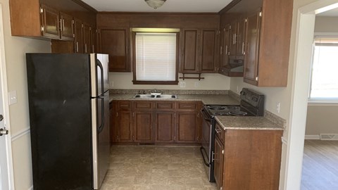 A kitchen with brown cabinets and a black refrigerator.