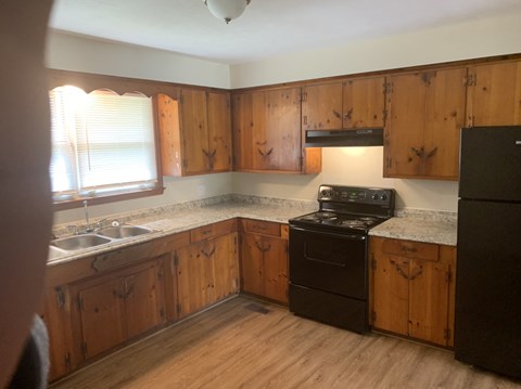 A kitchen with wooden cabinets and a black stove top oven.