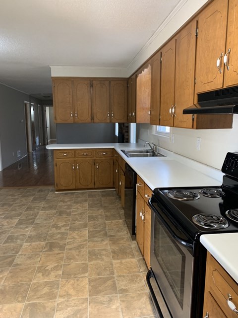 A kitchen with wooden cabinets and a black stove top oven.